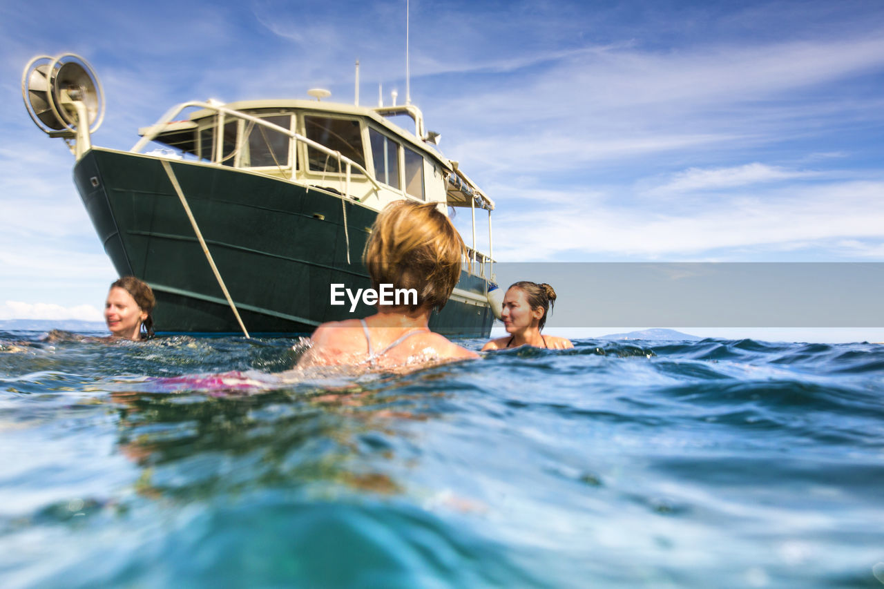 Women swimming in sea against sky