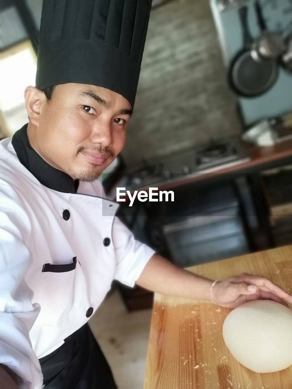 Portrait of chef touching dough at kitchen