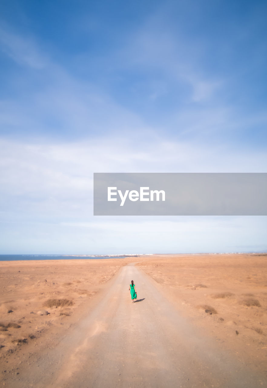 Mid distance view of woman walking on road at desert