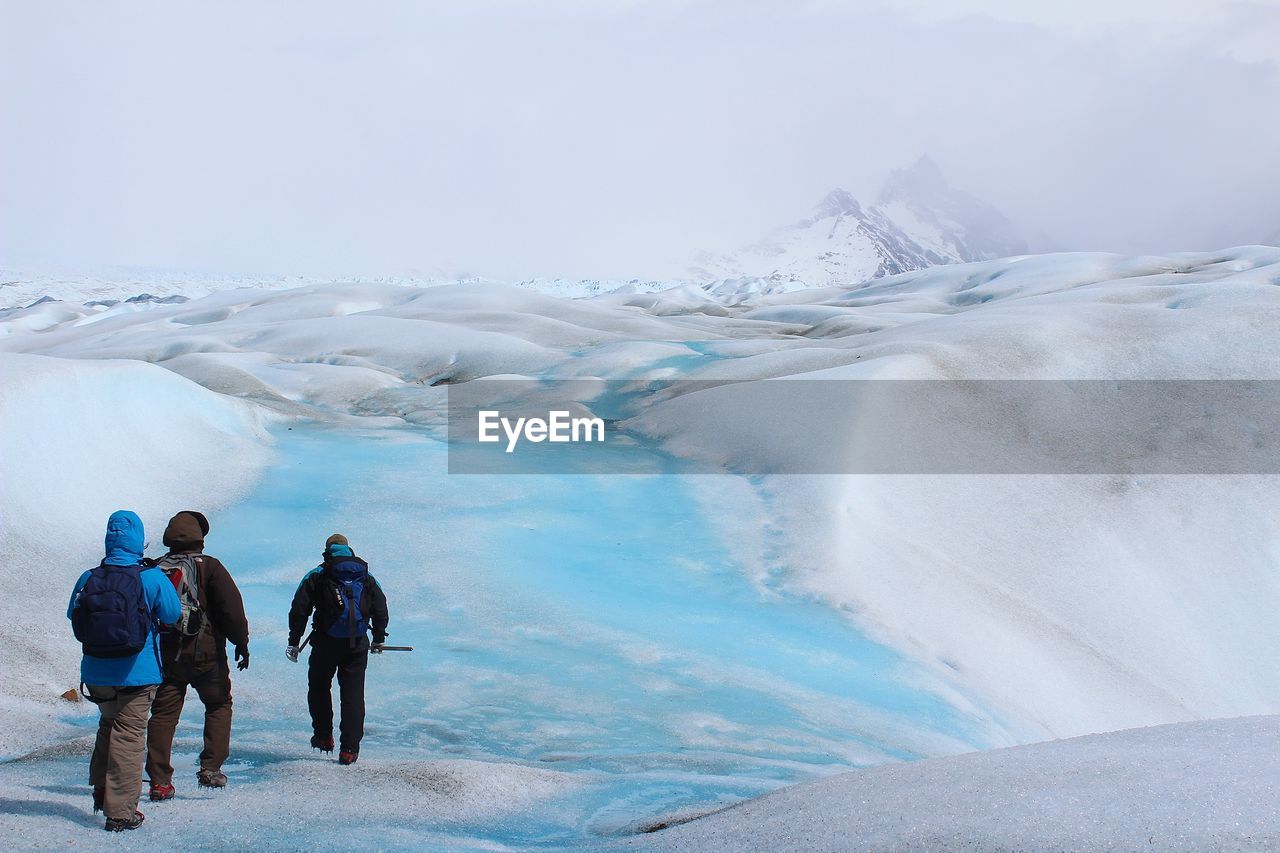 Rear view of people walking on glacier