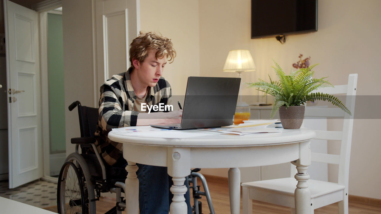 Young disabled man working at home office