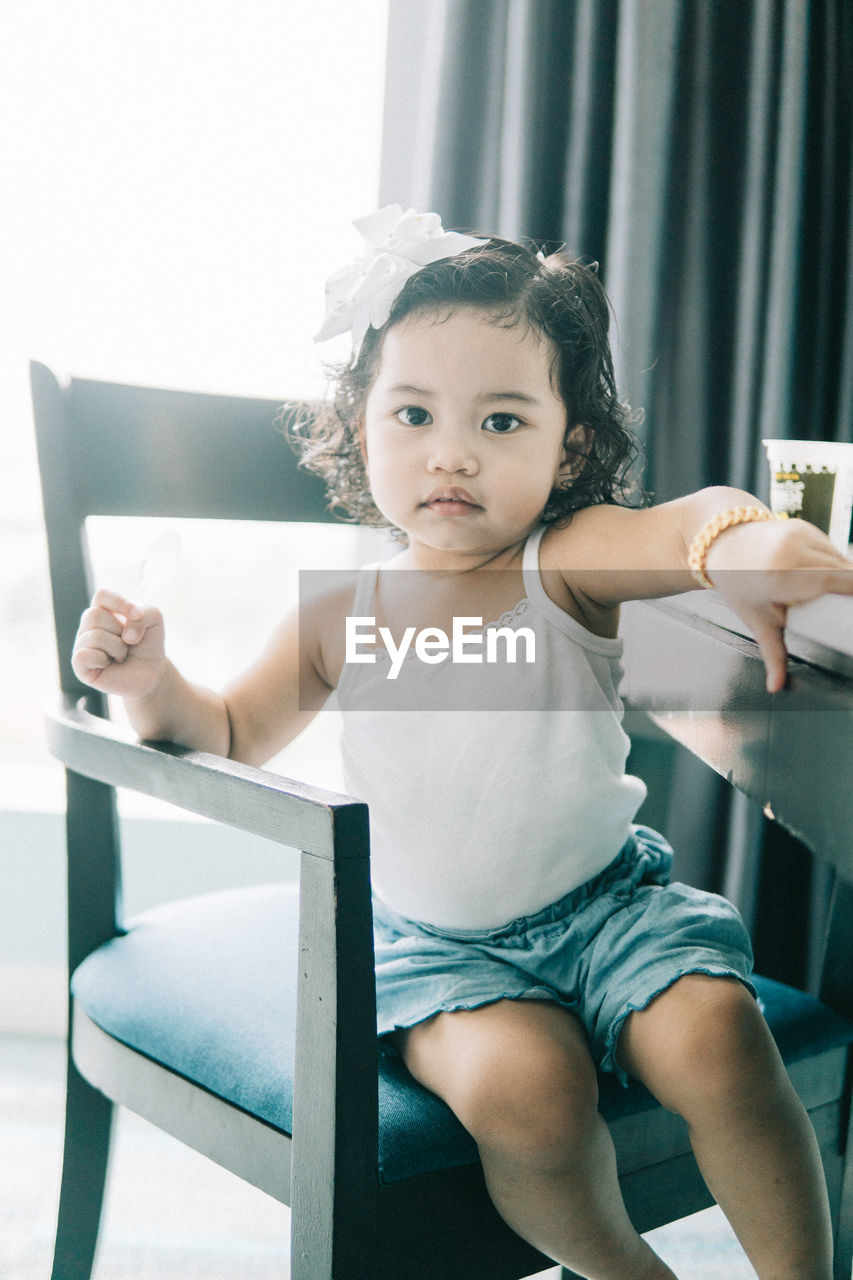 Cute girl sitting on chair at home