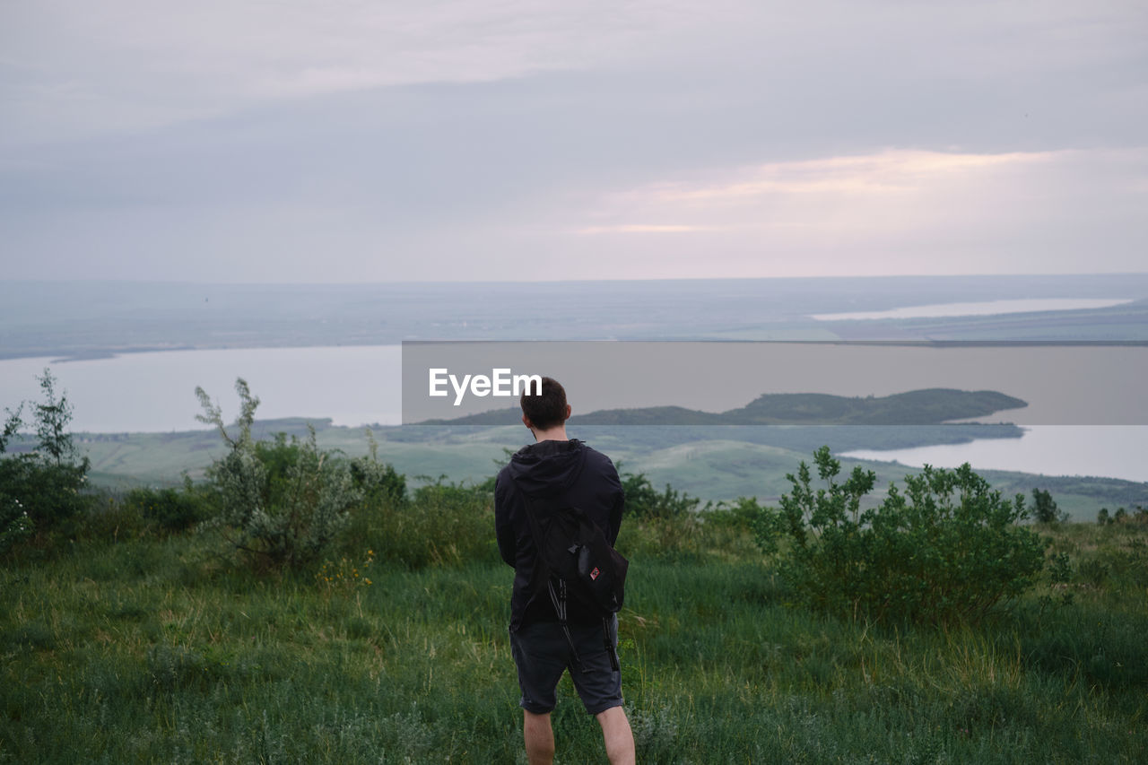 Rear view of man looking at view of sea against sky