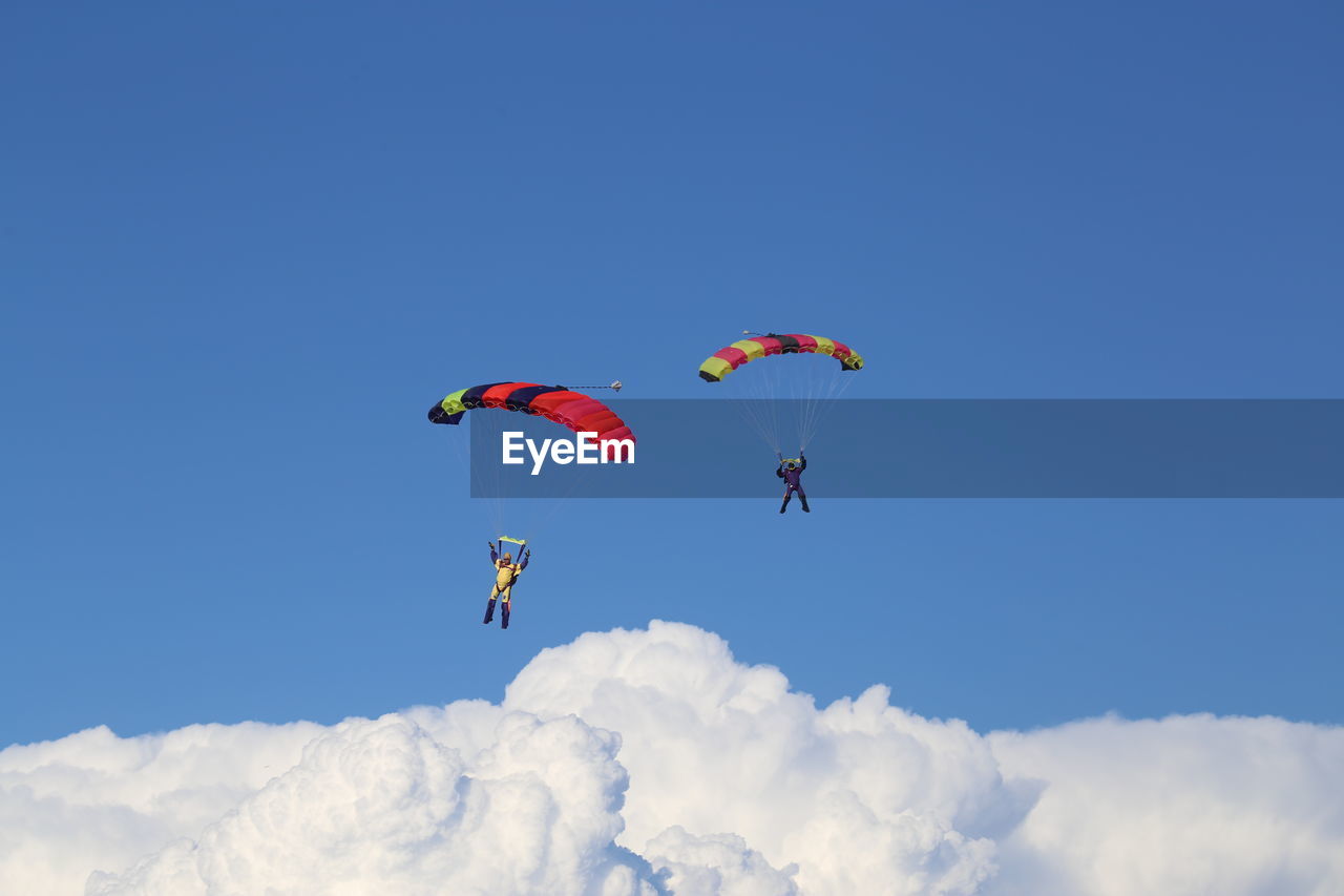 Scenic view of people paragliding against blue sky