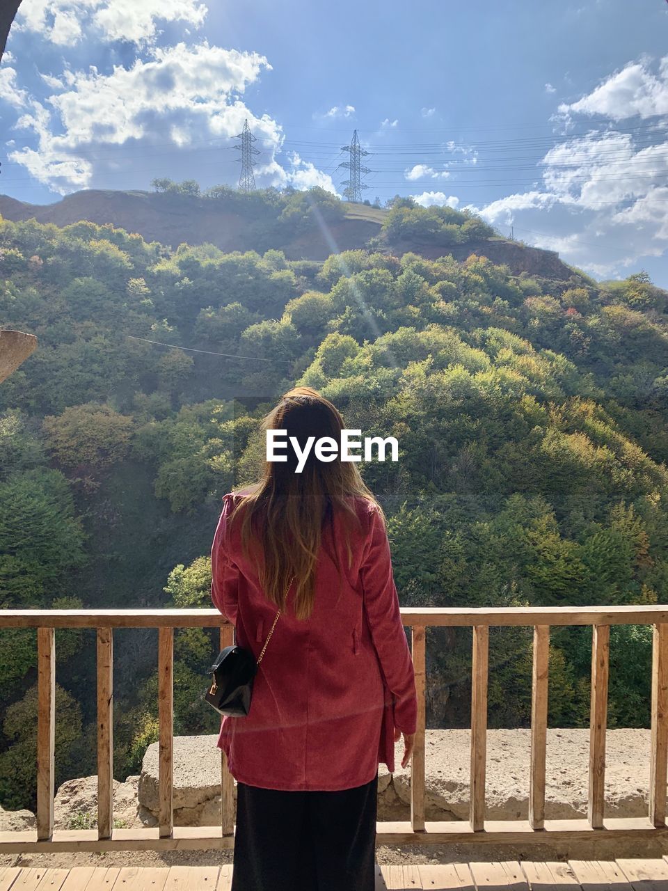 Rear view of woman standing by railing against sky