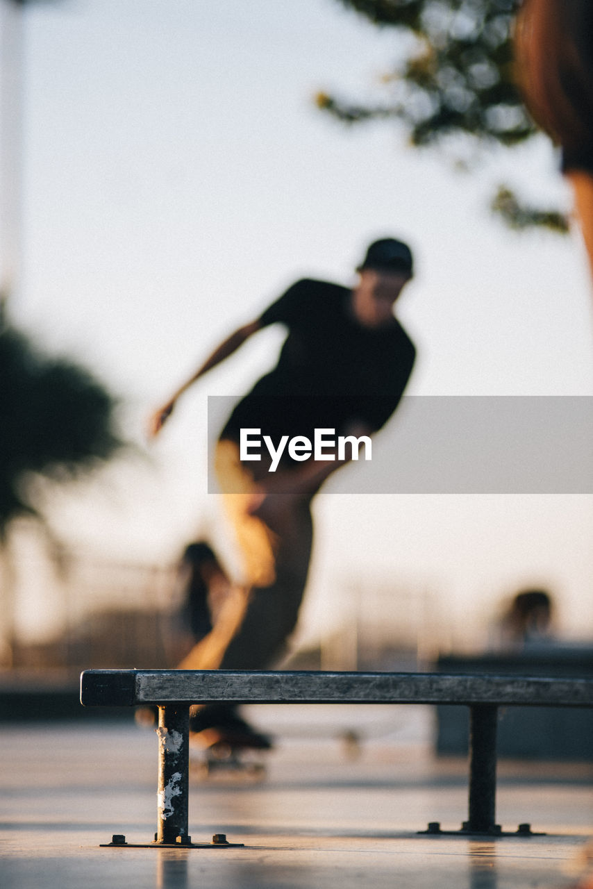 Man skateboarding at skateboard park with bench in foreground