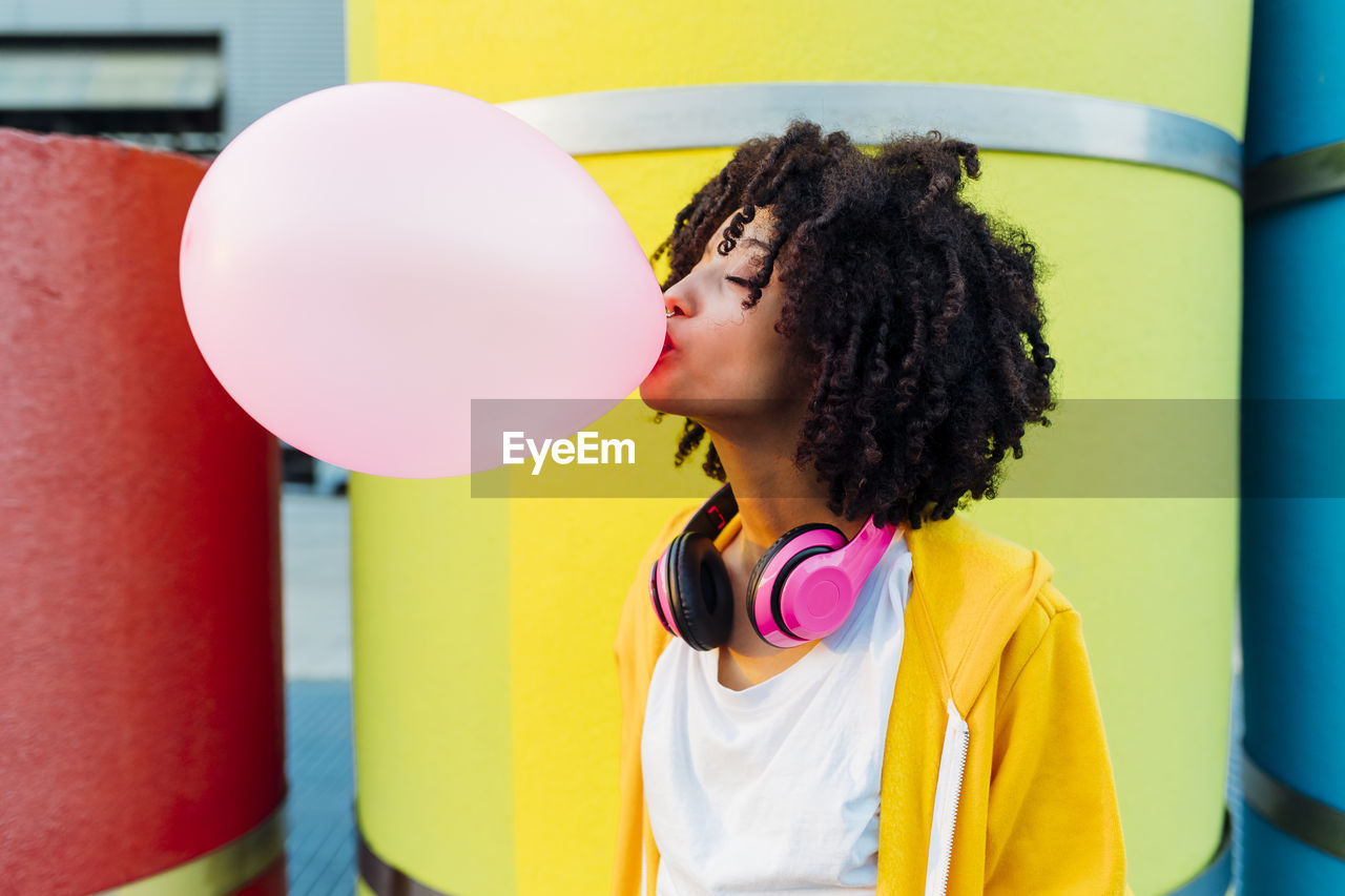 Young woman with eyes closed blowing bubble gum