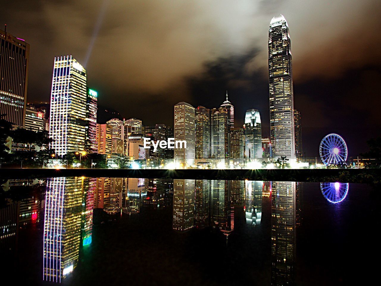 Reflection illuminated modern buildings on sea at night