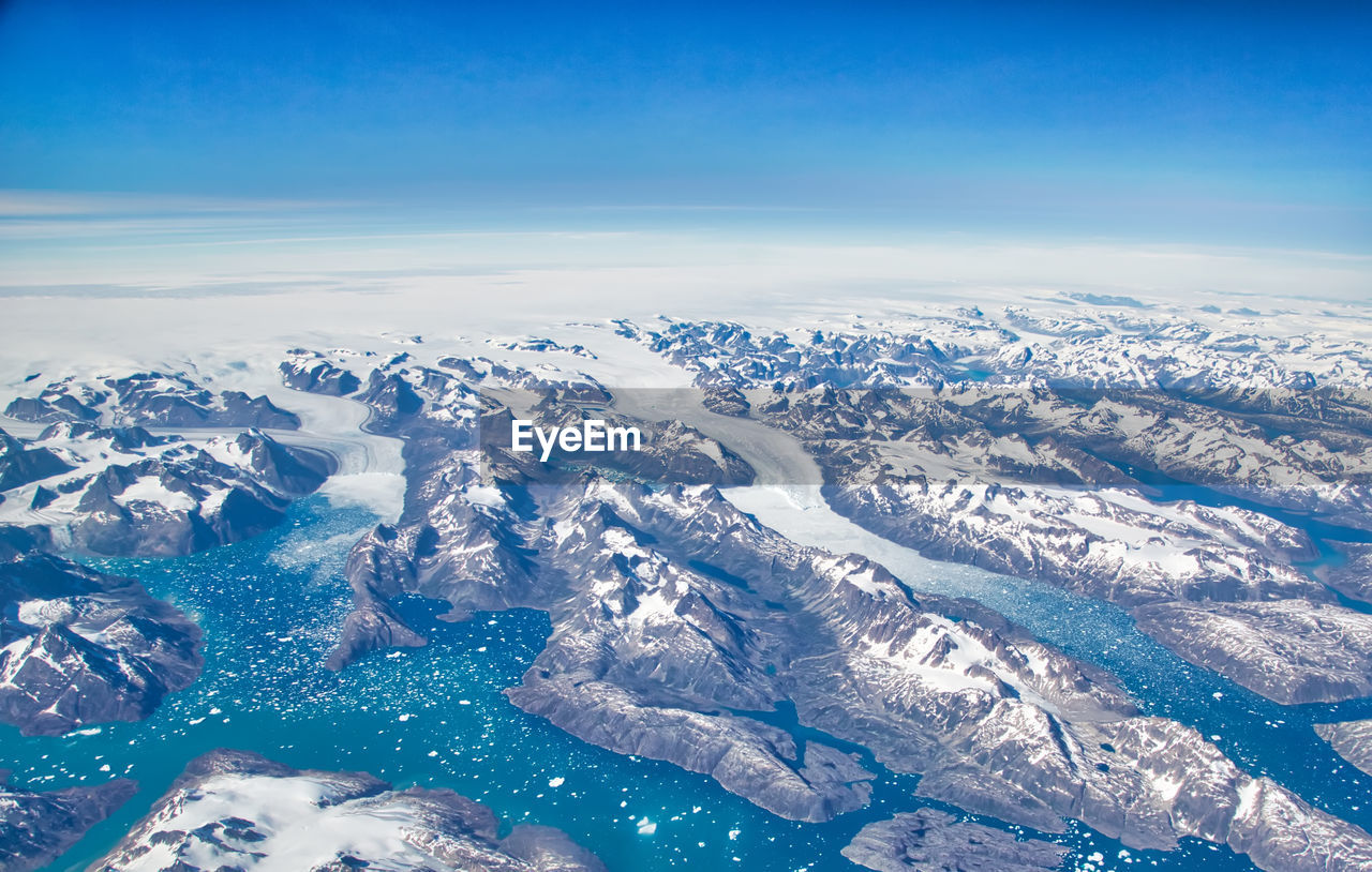 AERIAL VIEW OF SNOWCAPPED MOUNTAIN AGAINST BLUE SKY