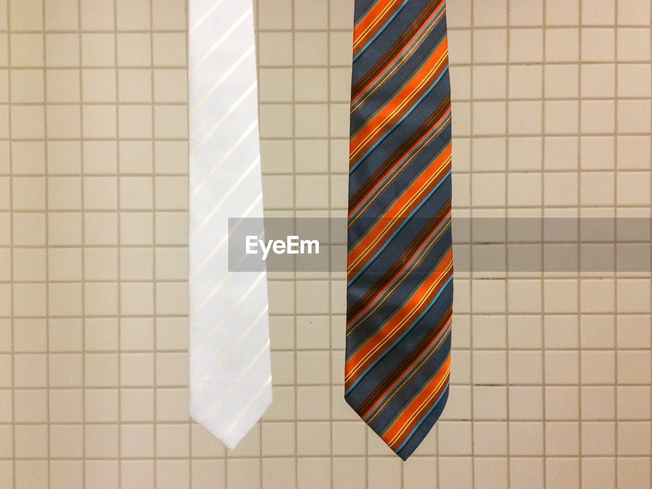 Close-up of neckties hanging against tiled wall