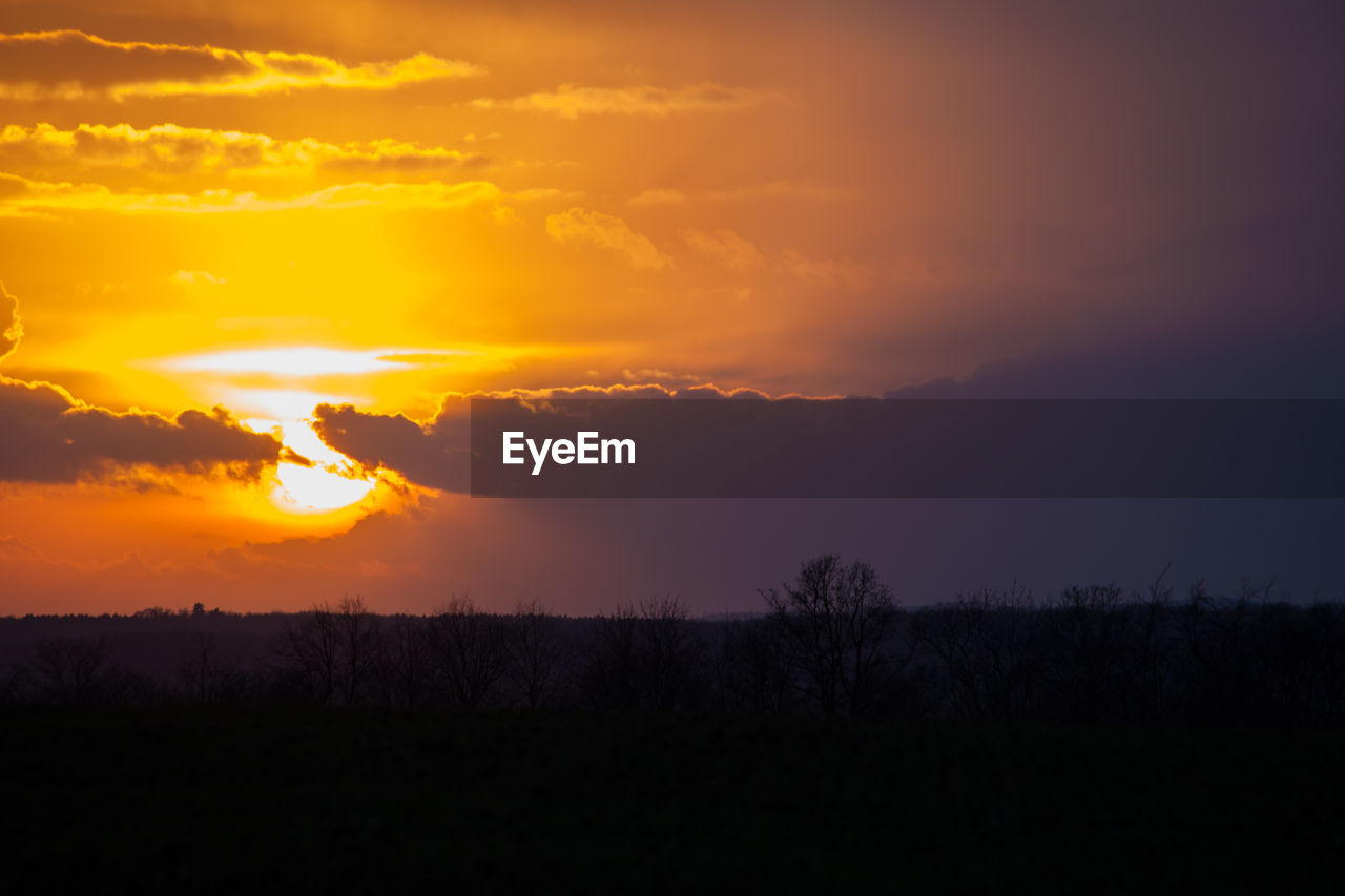 SCENIC VIEW OF SILHOUETTE FIELD AGAINST SKY AT SUNSET