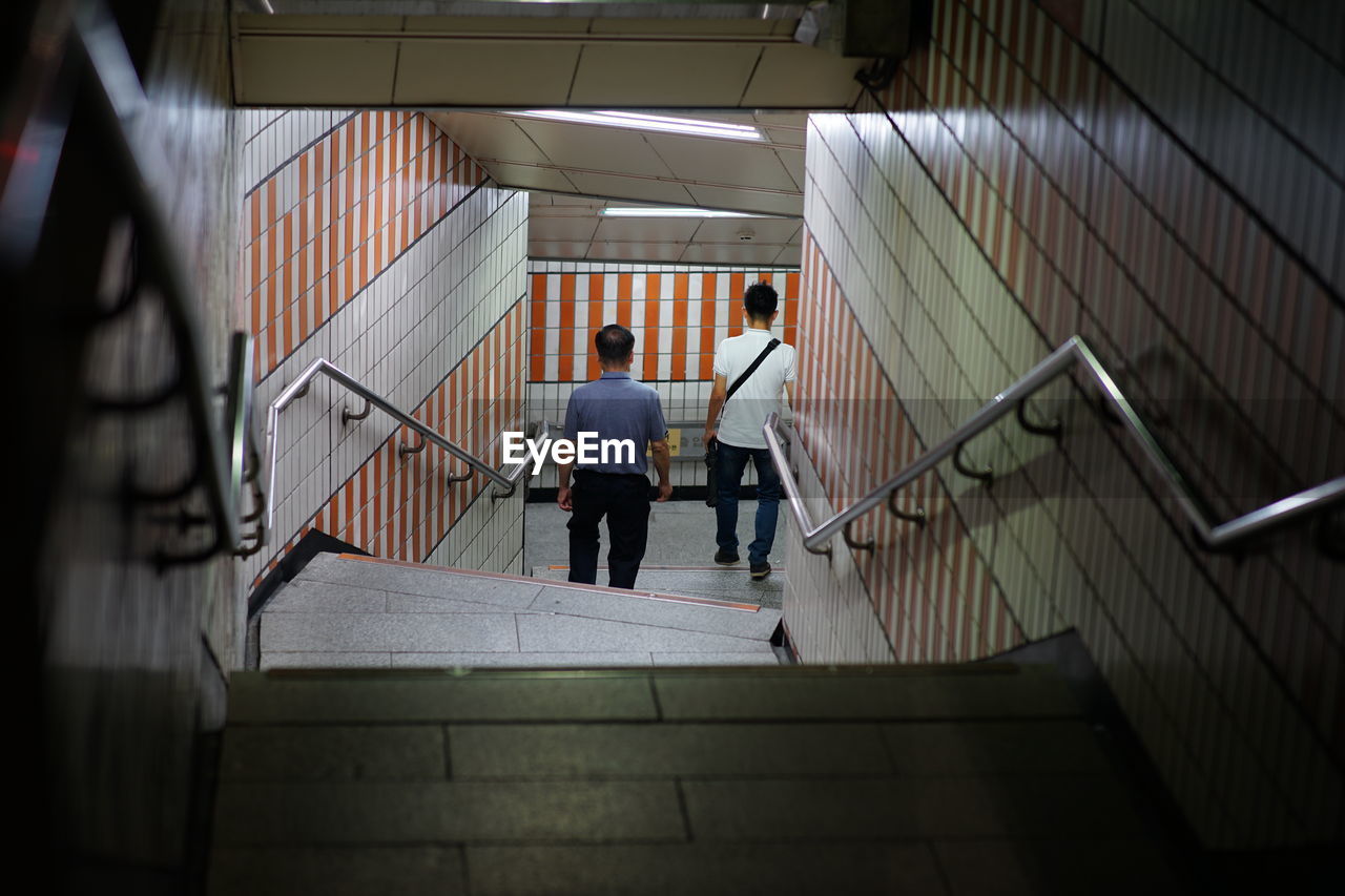 Rear view of men on staircase in subway