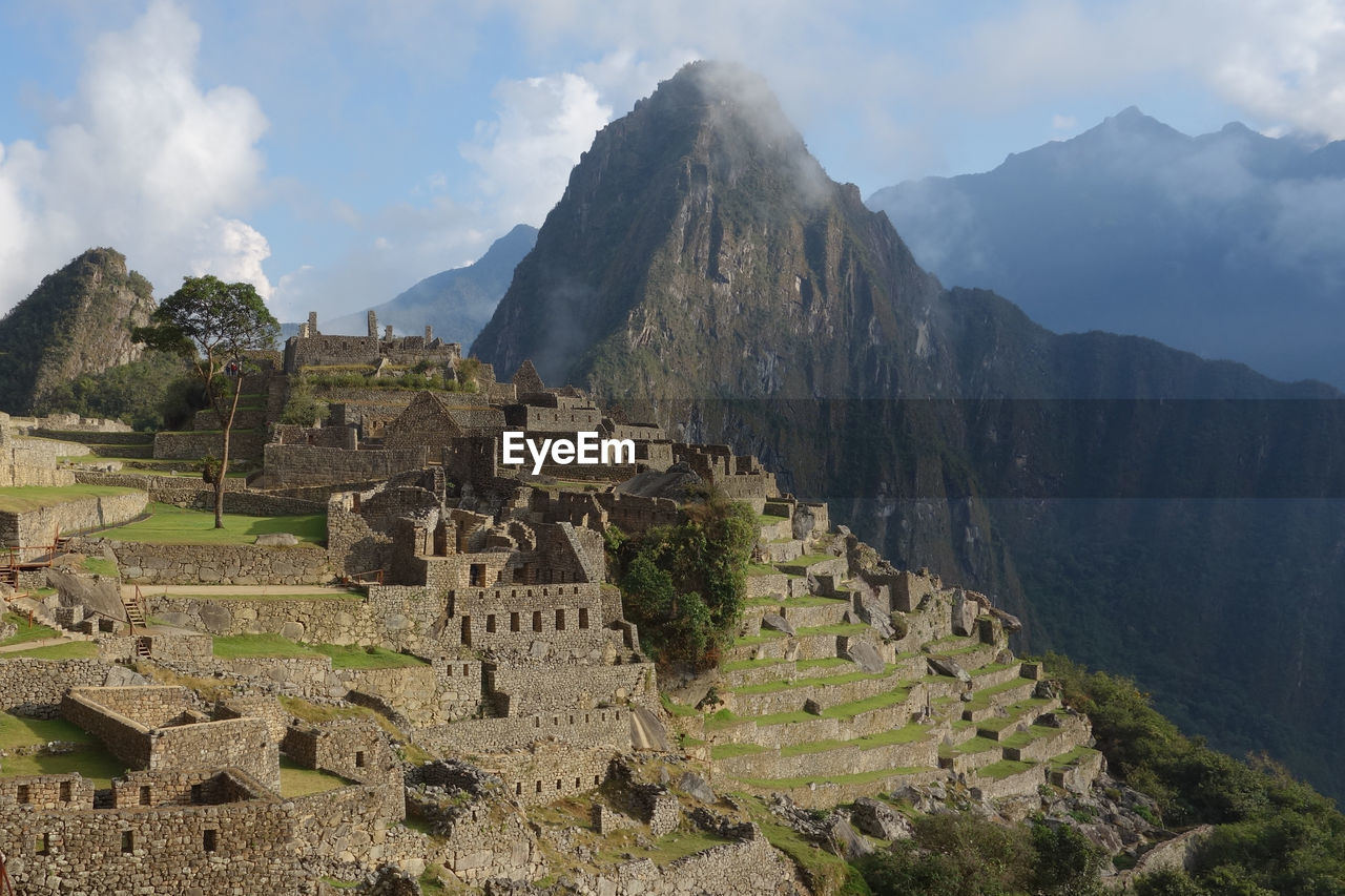 Mach picchu ruins of mountains against cloudy sky