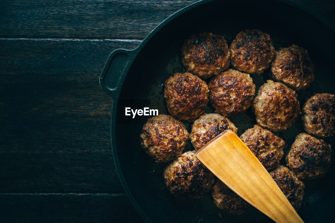 Spatula with meatballs in cooking pan