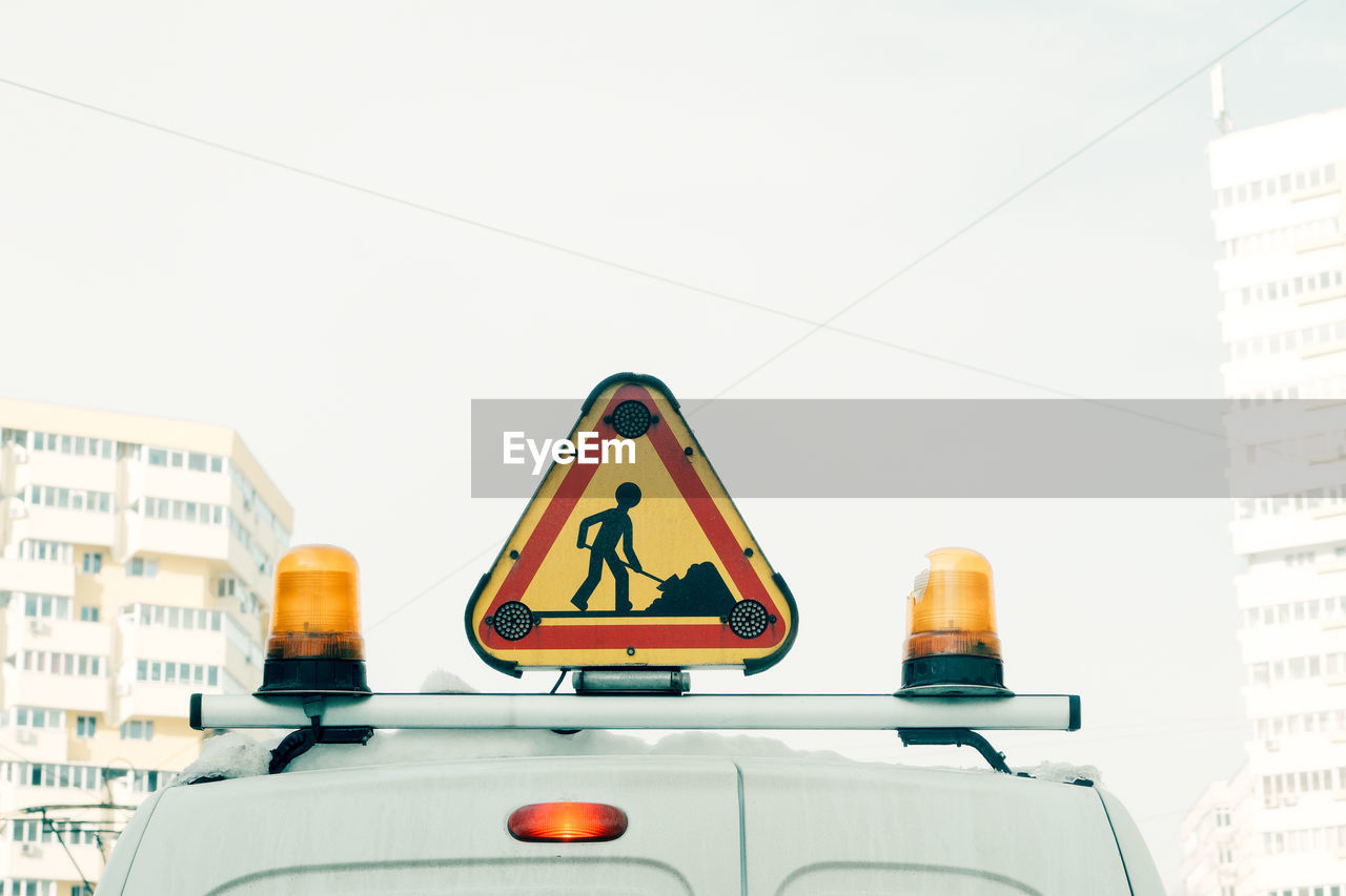 Close-up of road sign on vehicle in city against clear sky