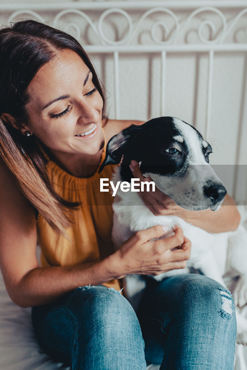 PORTRAIT OF WOMAN WITH DOG SITTING ON SOFA