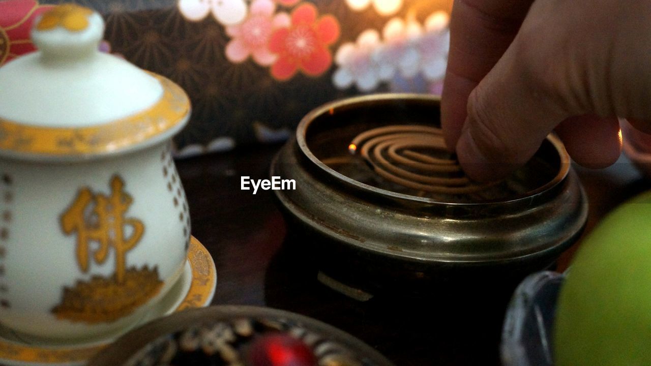 Cropped hand placing mosquito coil in container