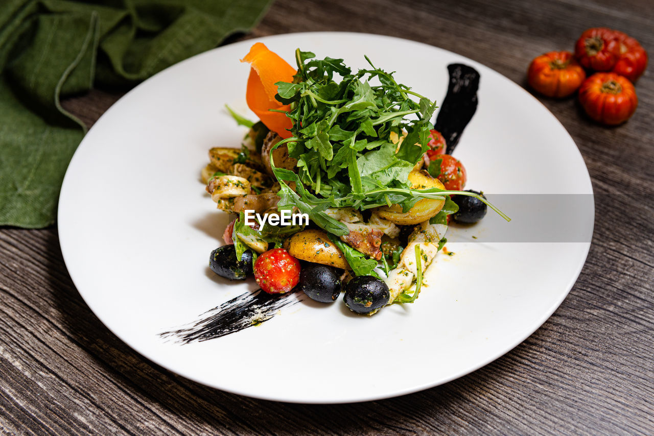 Italian salad with octopus in ligurian style. arugula, black olives, cherry tomatoes, octopus.