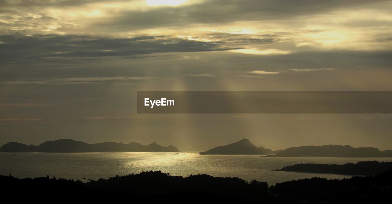 SCENIC VIEW OF SEA AND SILHOUETTE MOUNTAINS AGAINST SKY