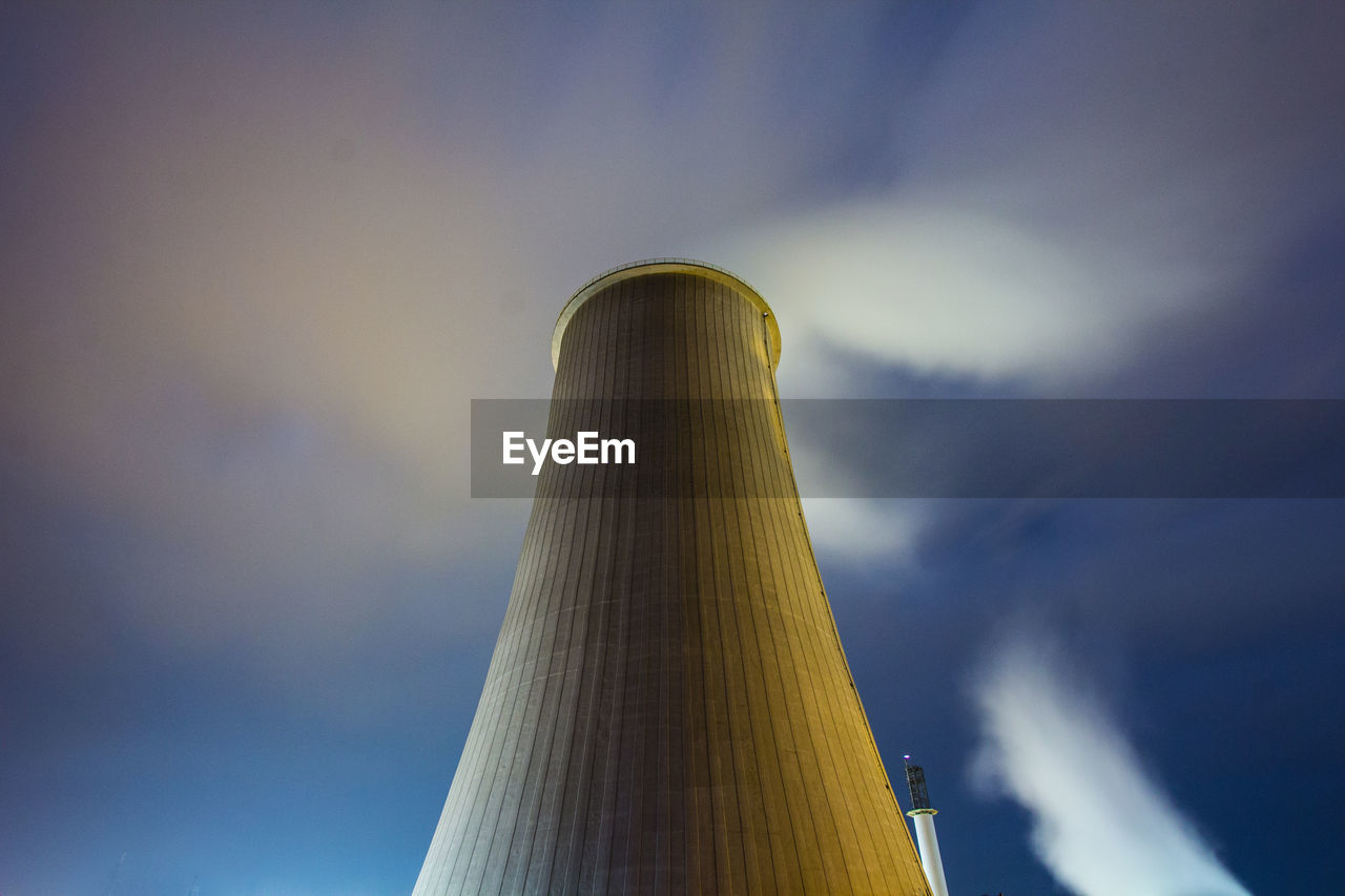 Low angle view of smoke stack emitting air pollution against sky at night