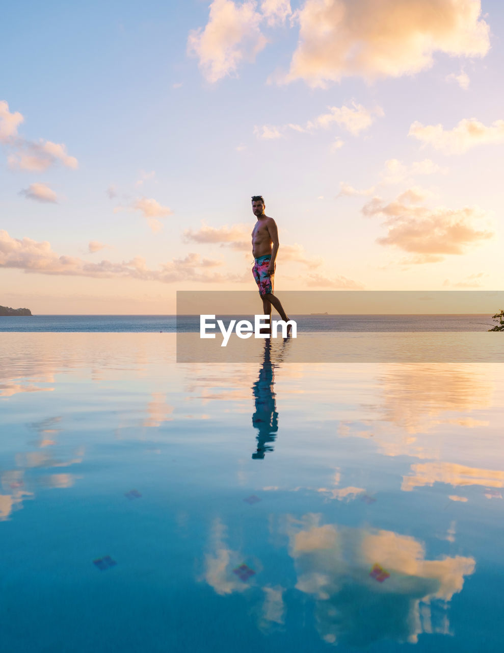 rear view of woman walking at beach against sky during sunset