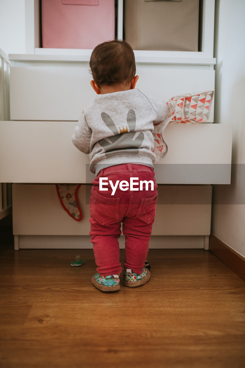 REAR VIEW OF BOY STANDING ON HARDWOOD FLOOR