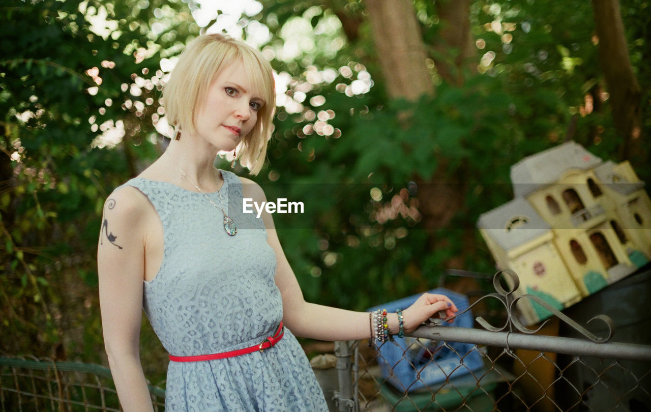 Portrait of woman standing by railing at yard