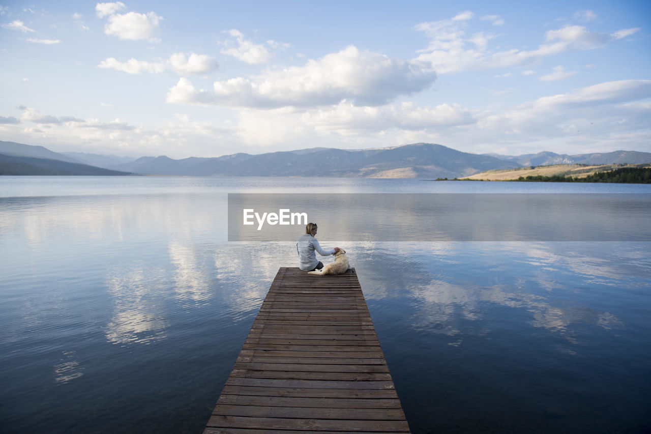 A woman and her dog enjoying an evening on the docks on hebgen lake.