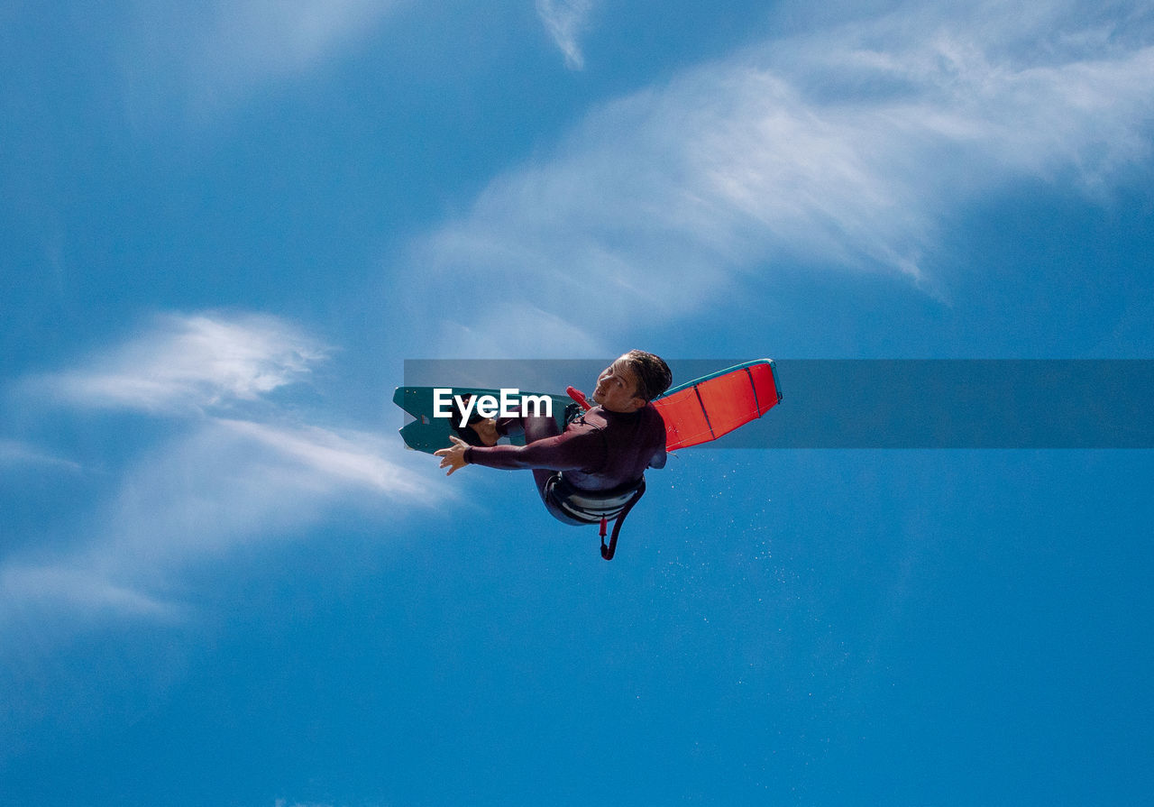 Low angle view of man surfboarding against blue sky