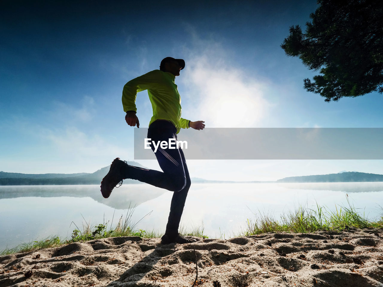 MAN ON ROCK IN SEA AGAINST SKY