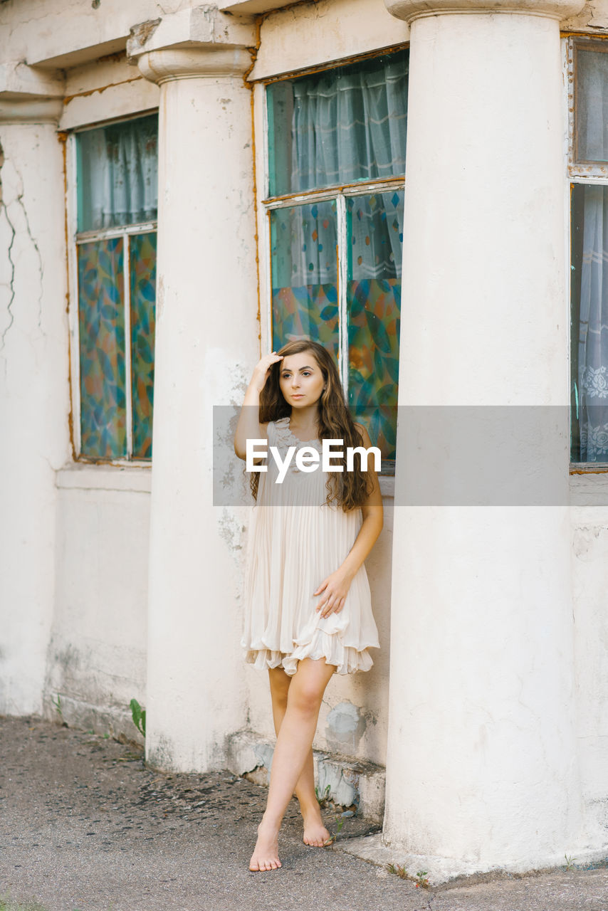 Portrait of a beautiful girl in a summer dress with long hair, who holds her hand in her hair