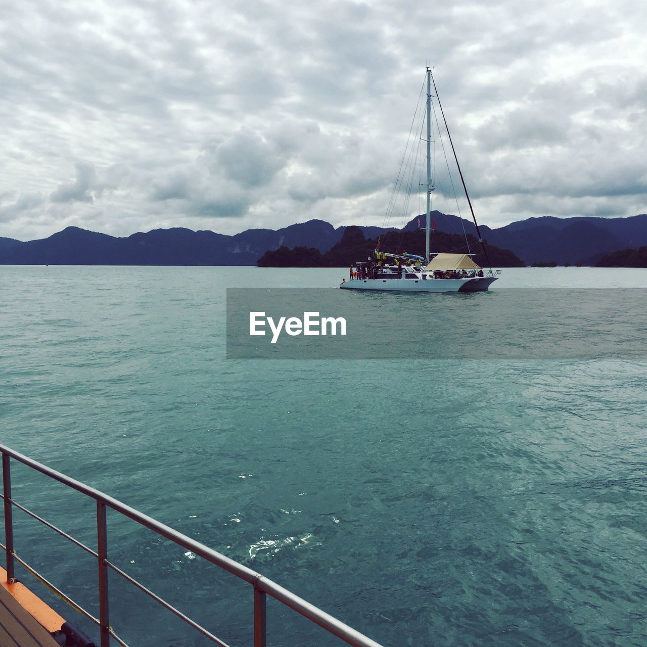 Boats sailing in sea against cloudy sky