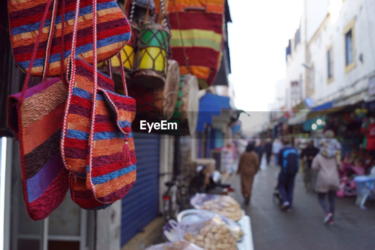 Close-up of multi colored shoulder bags hanging for sale in market