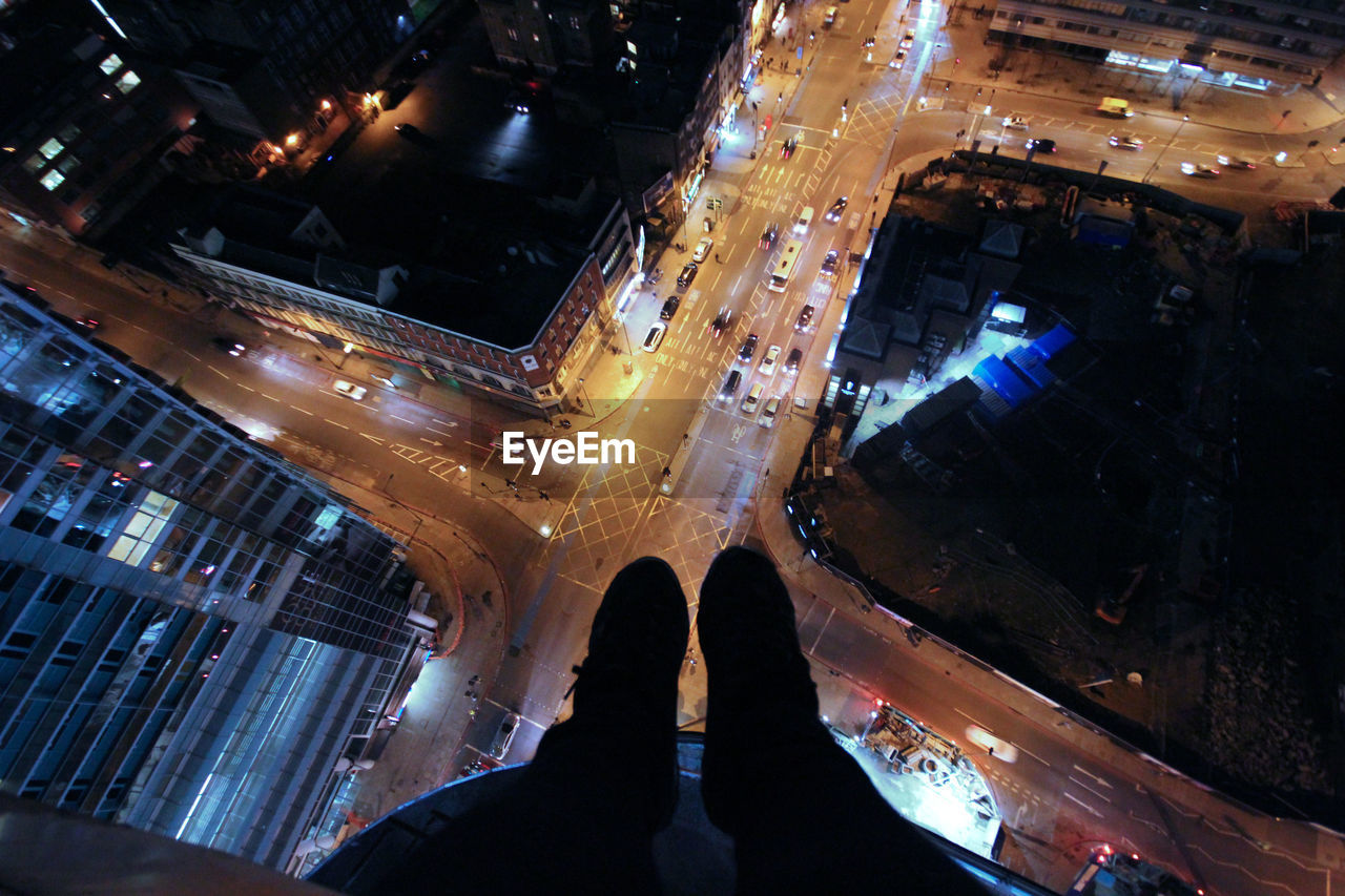 Low section of people standing on illuminated city at night