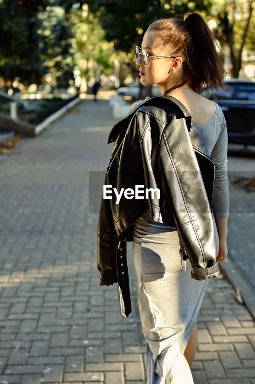 Rear view of woman standing on footpath