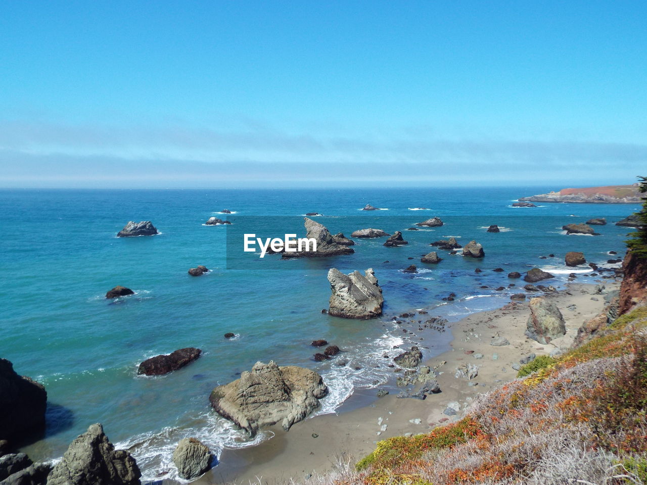 SCENIC VIEW OF SEA AND ROCKS AGAINST BLUE SKY