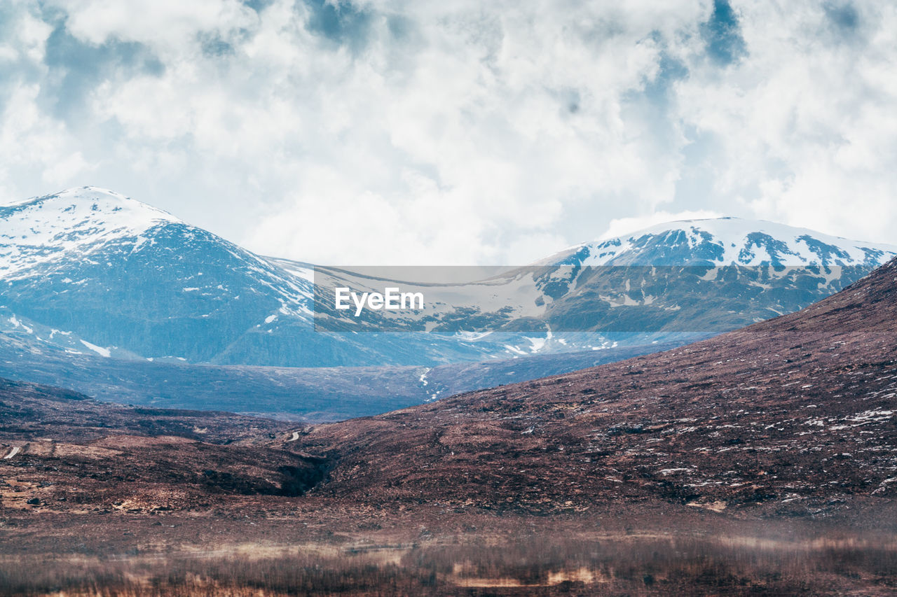 Scenic view of snowcapped mountains against cloudy sky