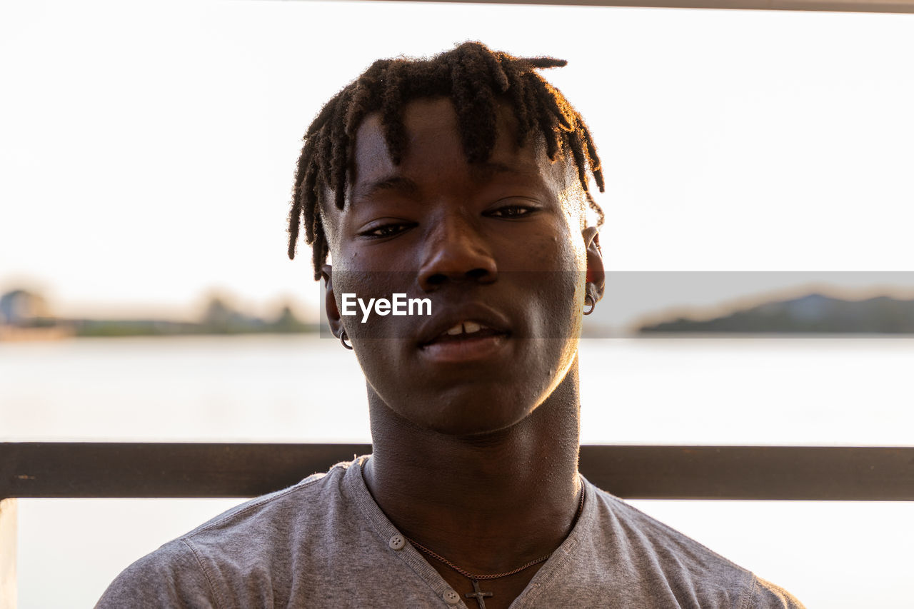 portrait, one person, headshot, men, water, adult, person, front view, young adult, relaxation, casual clothing, lifestyles, focus on foreground, day, nature, looking at camera, emotion, outdoors, sunlight, architecture, smiling, leisure activity, sea, close-up, looking, sky, human face, city