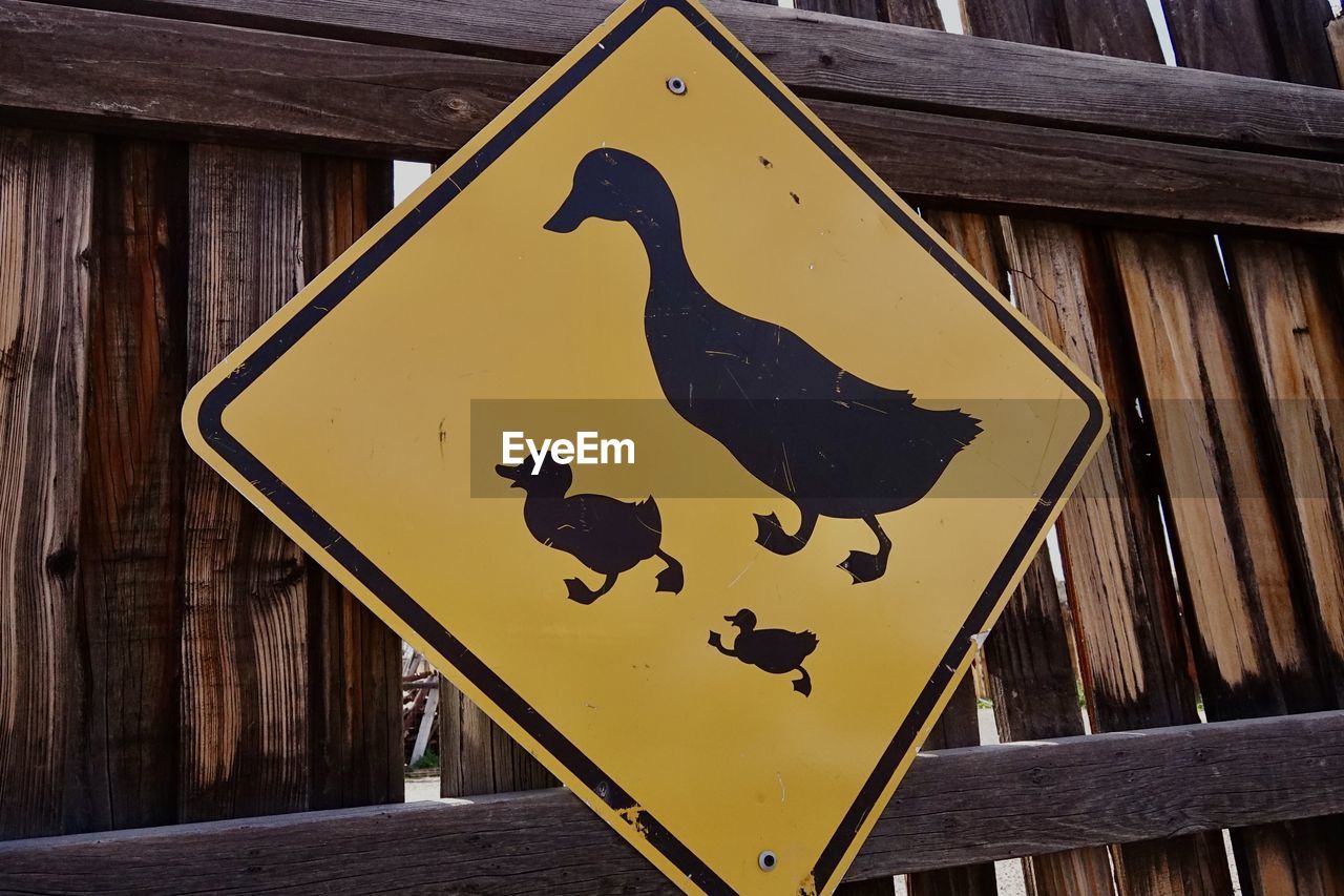 A yellow street sign with duck symbols warning of a crossing area.