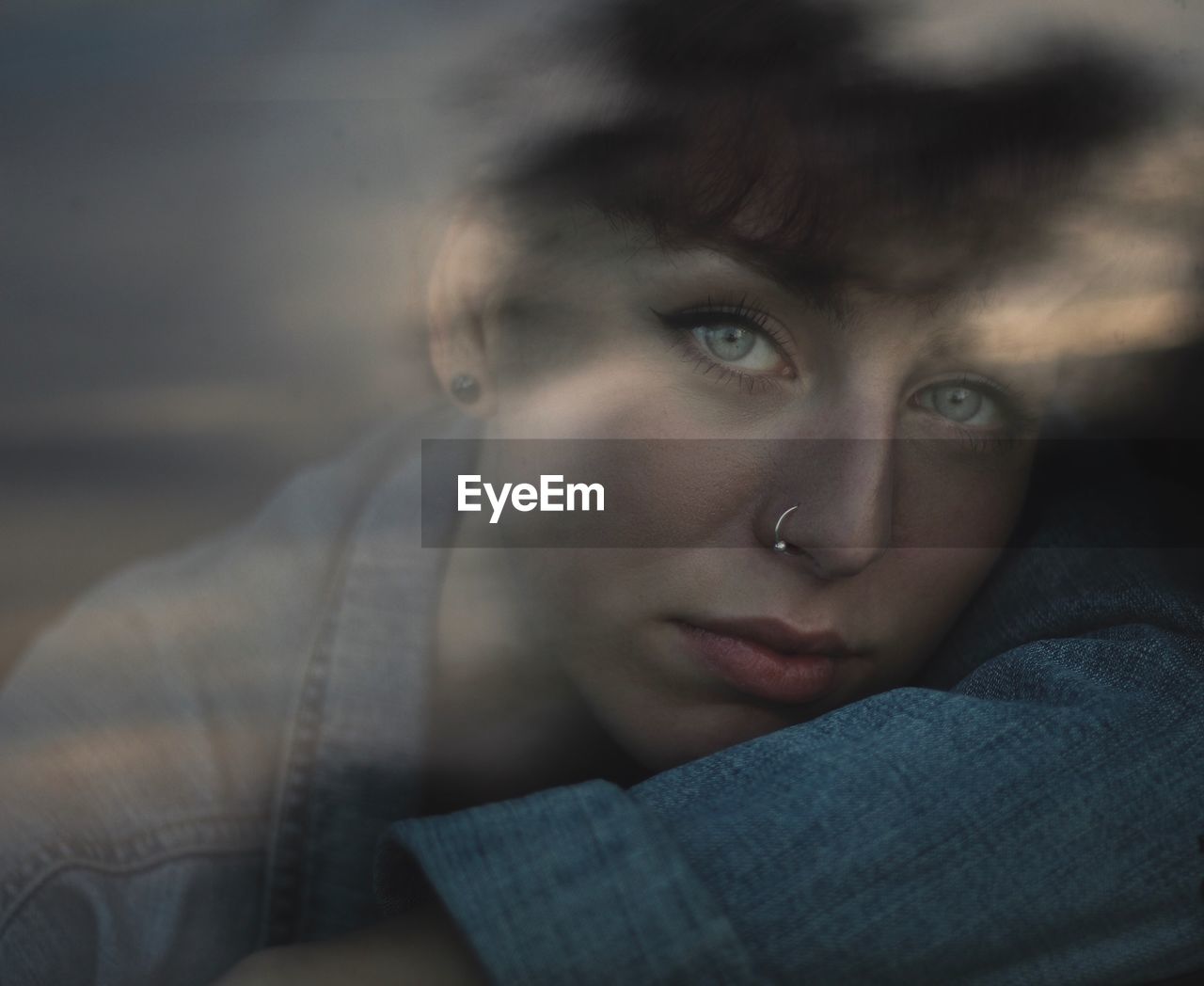 Close-up portrait of young woman seen through window during sunset