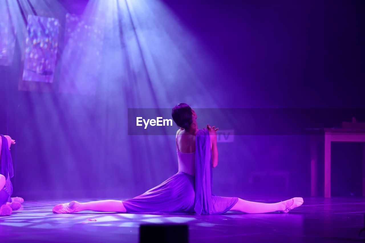 Rear view of woman dancing against illuminated lights