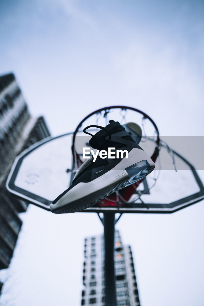 Low angle view of shoes and basketball hoop against sky