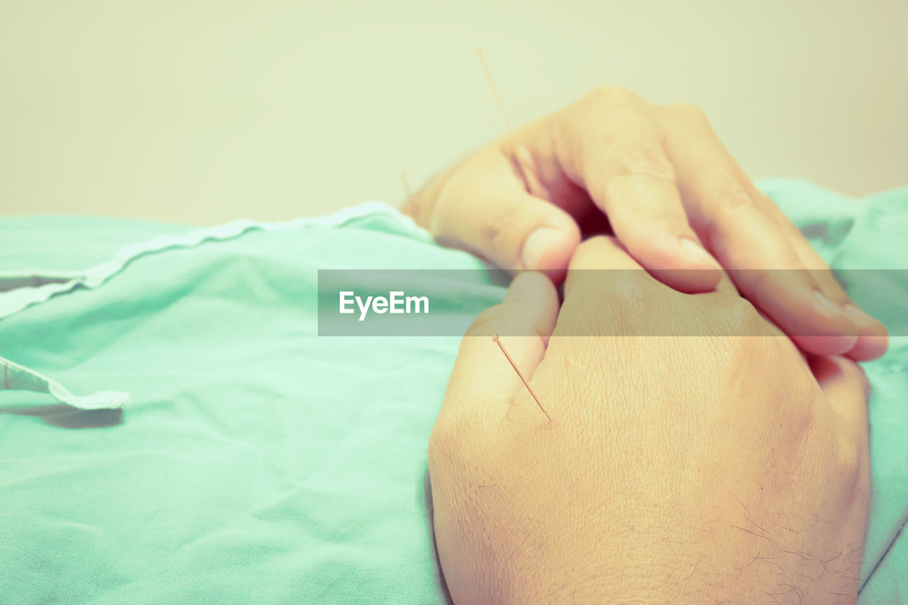 Midsection of man with acupuncture needles in clinic