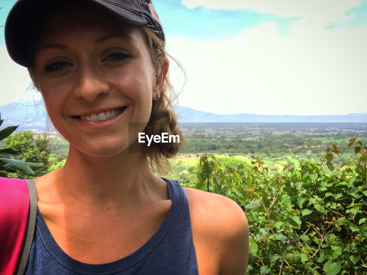 Portrait of smiling young woman standing against sky