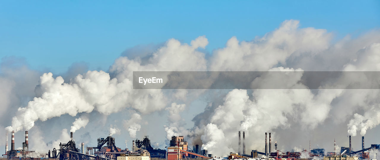 PANORAMIC VIEW OF SMOKE EMITTING FROM INDUSTRY AGAINST SKY