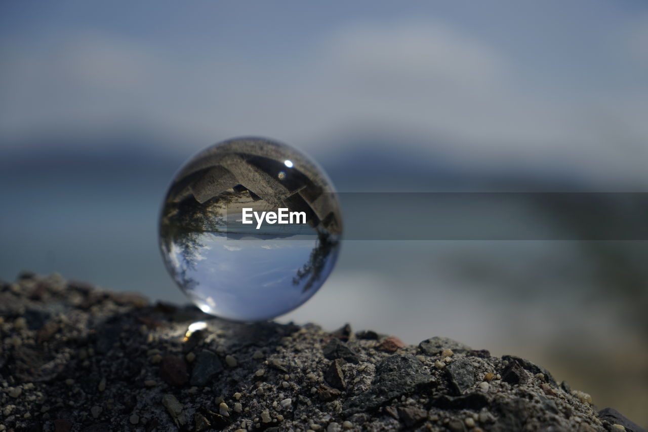 CLOSE-UP OF CRYSTAL BALL ON ROCK AGAINST SKY