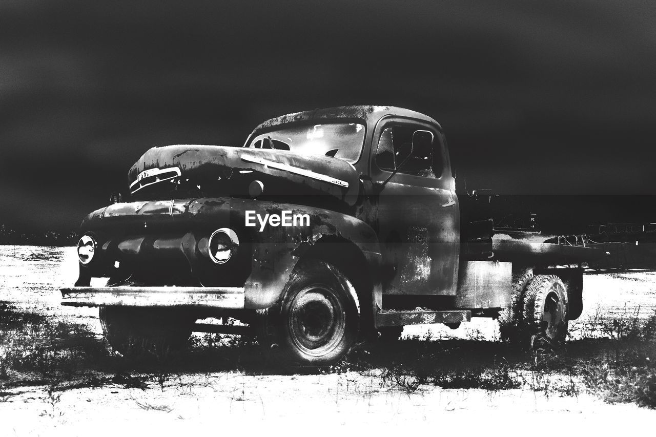 Abandoned truck on snow covered field at dusk