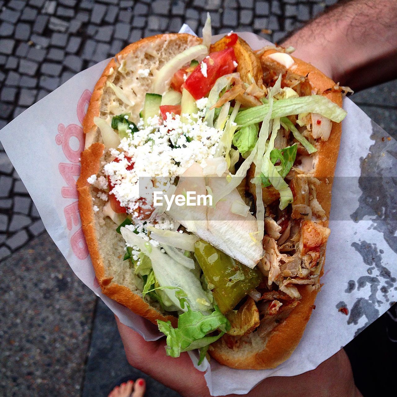 Cropped image of hand holding chicken kebab with bread