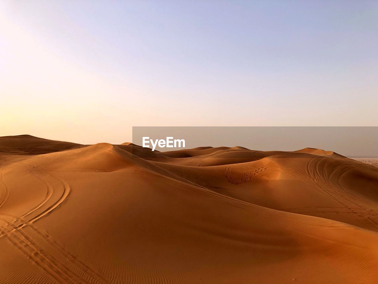 Scenic view of desert against clear sky during sunset