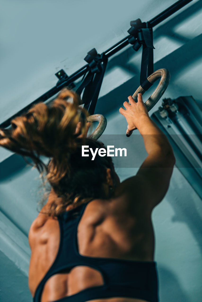 Low angle view of woman holding gymnastic rings 